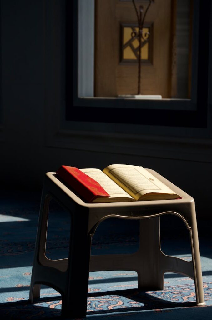 Open Quran on a stand in a mosque with sunlight streaming through a window in Istanbul, Türkiye.